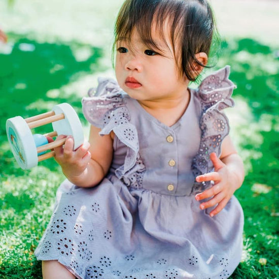 Baby girl playing outside with Orange Tree activity wooden toy