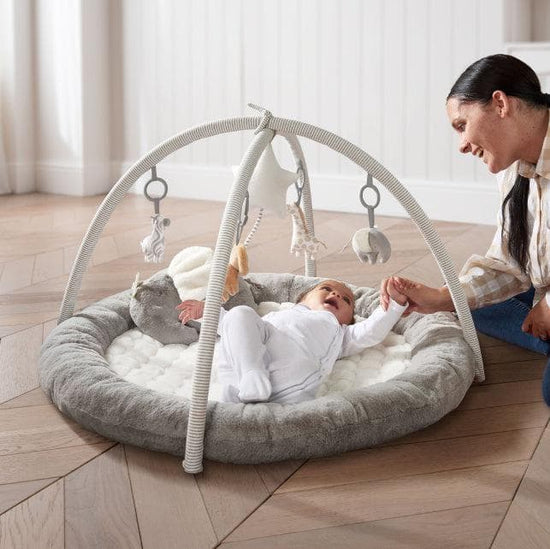 Baby laying down on grey Mamas & Papas playmat