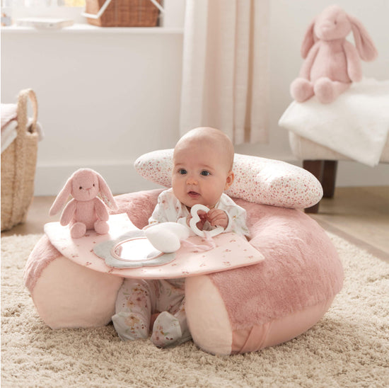 Baby sitting in Mamas & Papas pink sit & play toy